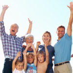 Full length of three generation family cheering in park with arms raised